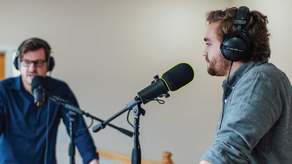 Two men recording a podcast with a mic pop filter highlighted in green